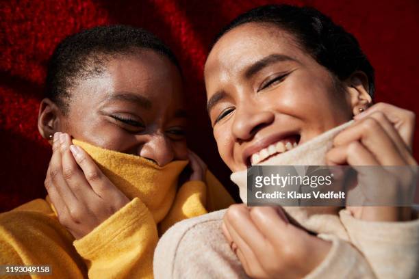smiling female friends against red wall - maglione foto e immagini stock