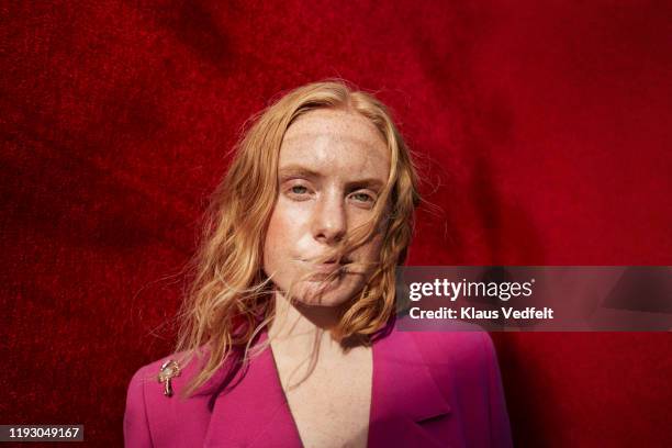 portrait of young woman standing against red wall - portrait fashion woman stock-fotos und bilder