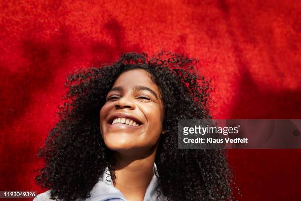 close-up of smiling woman against red wall - head back stock pictures, royalty-free photos & images
