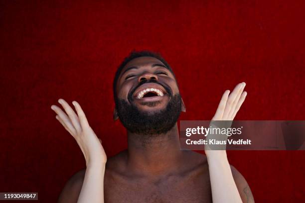 female hands raised in front of laughing man against red wall - hand on female chest stock pictures, royalty-free photos & images