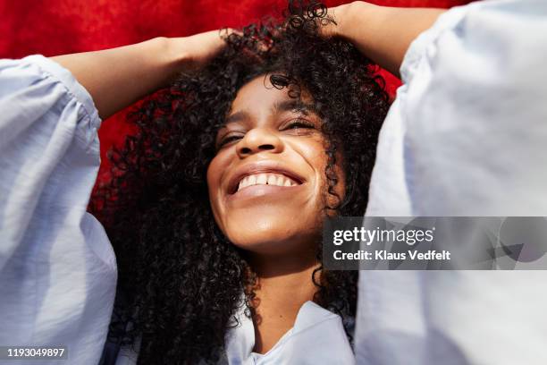 close-up of young woman against red wall - curly hair foto e immagini stock