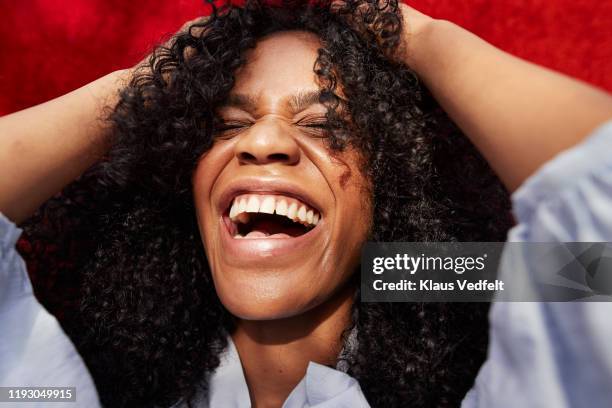 close-up of beautiful woman against red wall - afro jokes stock-fotos und bilder