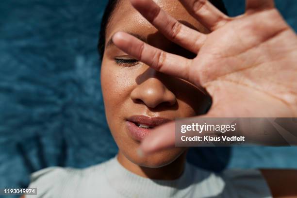 mixed race woman gesturing stop against blue wall - kopf in den händen stock-fotos und bilder