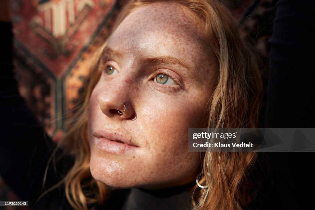 Woman looking away in sunlight against patterned wall