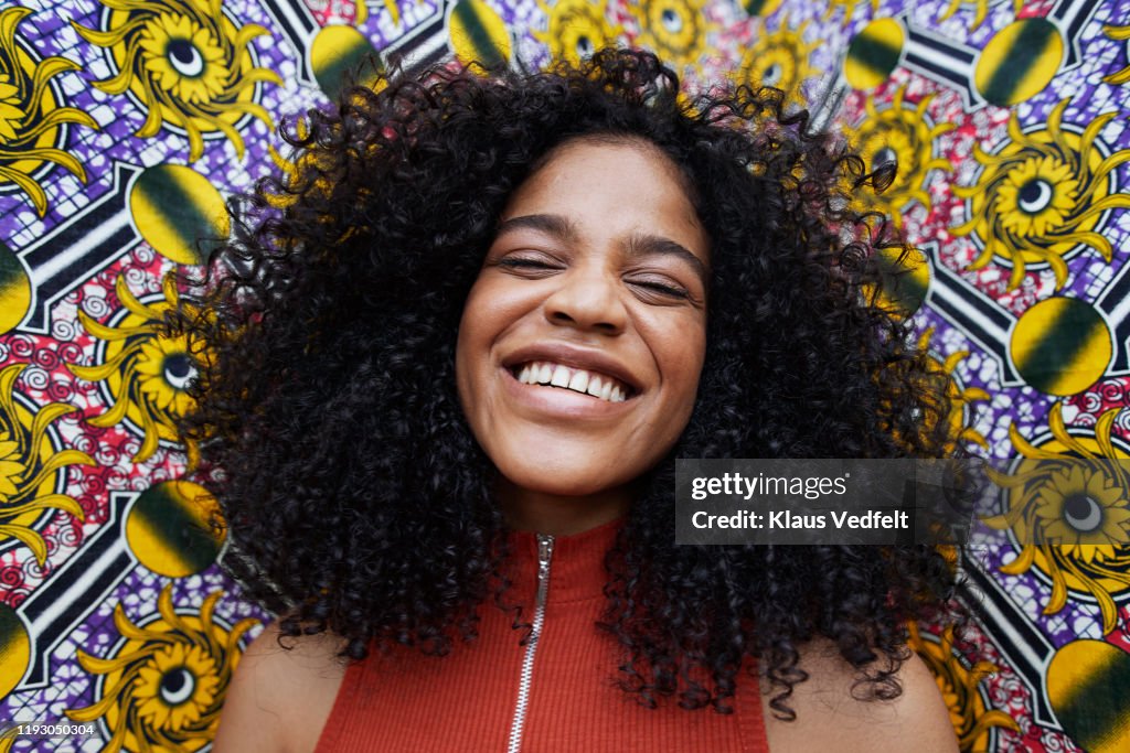 Happy young adult standing against patterned wall