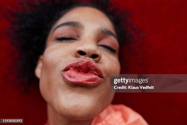 smiling woman puckering against red wall - kiss lips - fotografias e filmes do acervo