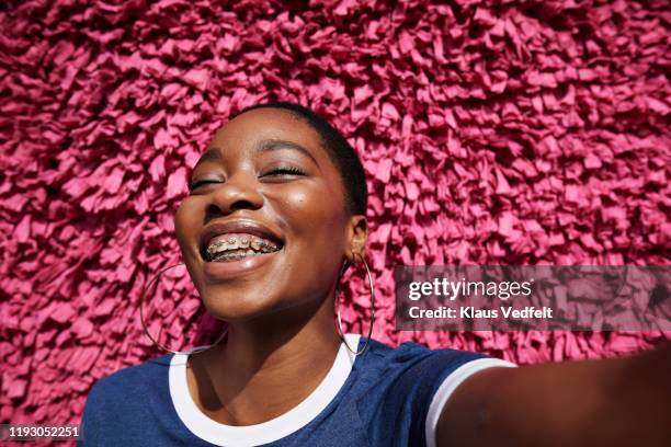 portrait of smiling woman against textured wall - pink and black braces stockfoto's en -beelden