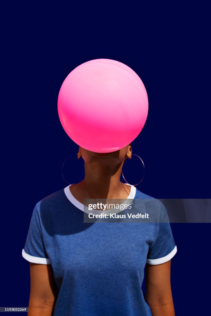 Obscured face of woman blowing balloon