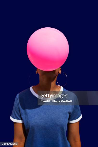 obscured face of woman blowing balloon - bright blue background stock pictures, royalty-free photos & images