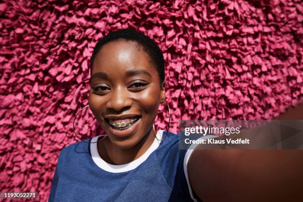 smiling woman with braces against textured wall - mensaje de móvil fotografías e imágenes de stock