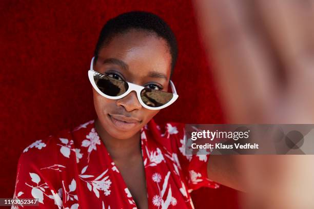 portrait of woman wearing sunglasses - portrait femme fond rouge adulte photos et images de collection