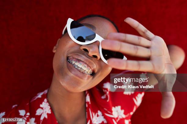 close-up of young woman gesturing against red wall - braces and smiles fotografías e imágenes de stock