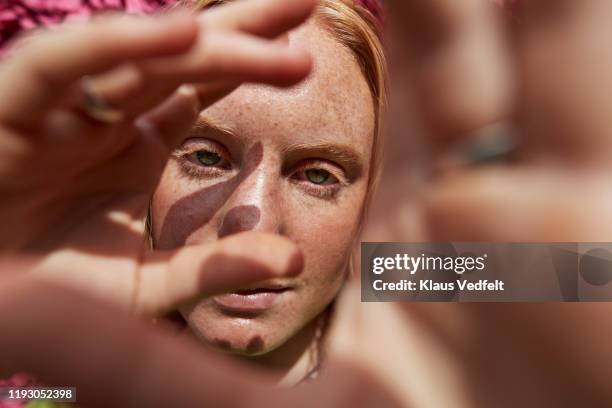 close-up of woman gesturing against textured wall - face sommersprossen stock-fotos und bilder