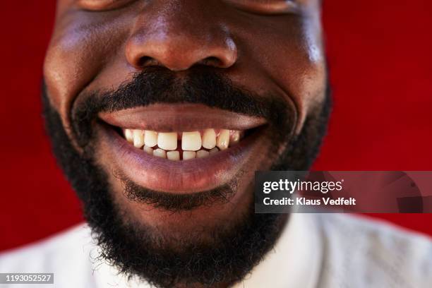 midsection of young man against red wall - sonrisa con dientes fotografías e imágenes de stock