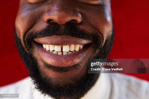 midsection of young man against red wall - bouche noir photos et images de collection
