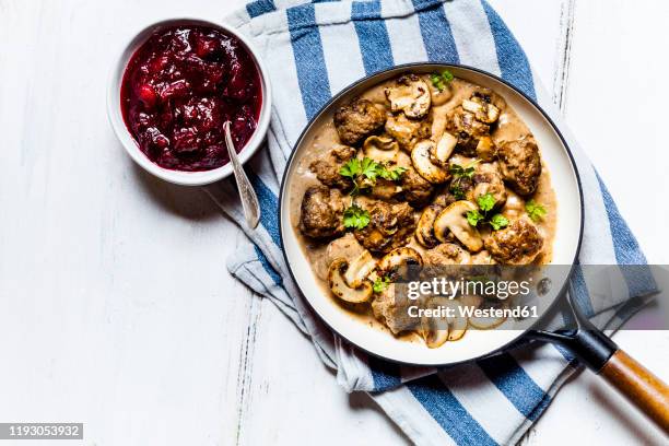 frying pan with swedishkottbullarmeatballs in mushroom gravy and bowl of mashed cranberries - ソース ストックフォトと画像