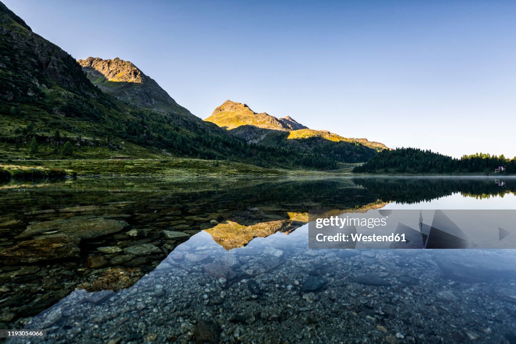 Austria, East Tyrol, Shiny lake reflecting mountains in Defereggen Valley