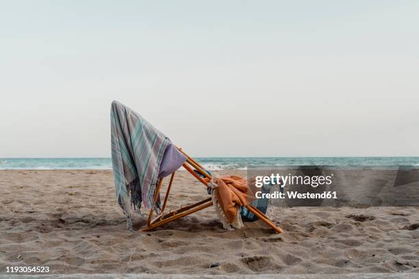 spain, province of barcelona, el garraf, beach towels hanging on deck chair left on sandy coastal beach at dusk - strandfilt bildbanksfoton och bilder