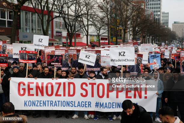 January 2020, Hamburg: Behind a banner with the inscription "Stop Genocide! Concentration camp #MadeinChina" people demonstrate against the...
