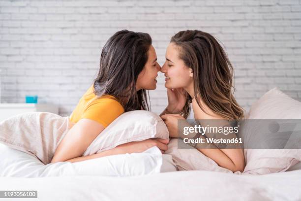 happy affectionate lesbian couple lying in bed - lesbian stockfoto's en -beelden