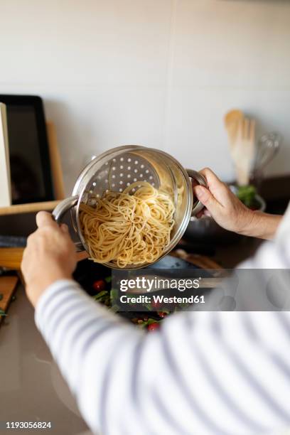 close-up of woman cooking pasta dish in kitchen at home - colander stockfoto's en -beelden