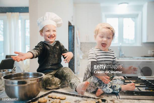 kleine chef vervelend zijn zusje in de keuken - kid chef stockfoto's en -beelden