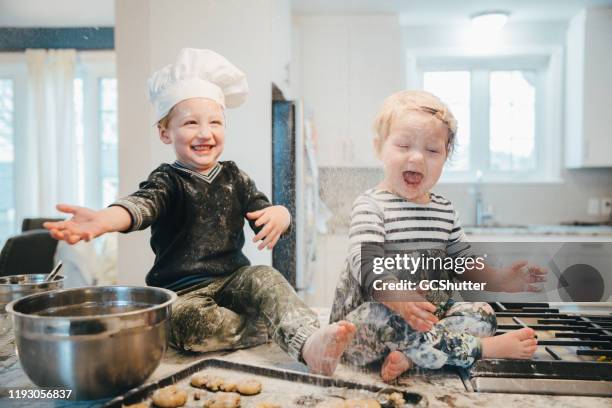 little chef annoying his baby sister at the kitchen - bad brother stock pictures, royalty-free photos & images