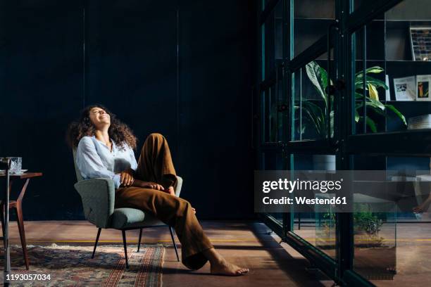young businesswoman relaxing in loft office - sitting in a chair stockfoto's en -beelden