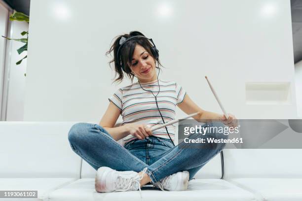 smiling woman listening to music and playing with drum sticks - drumstok stockfoto's en -beelden