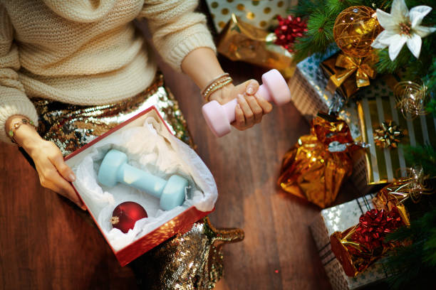 housewife holding christmas present box and dumbbells - fitness gift stock pictures, royalty-free photos & images