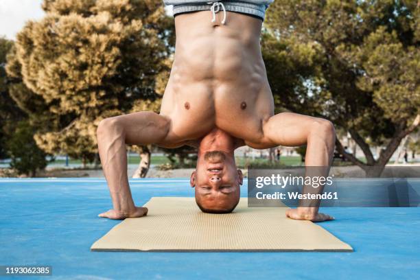 barechested muscular man pdoing a headstand outdoors - short trees bildbanksfoton och bilder