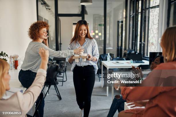 businesswoman serving coffee to colleagues in office - coffee break office stock-fotos und bilder