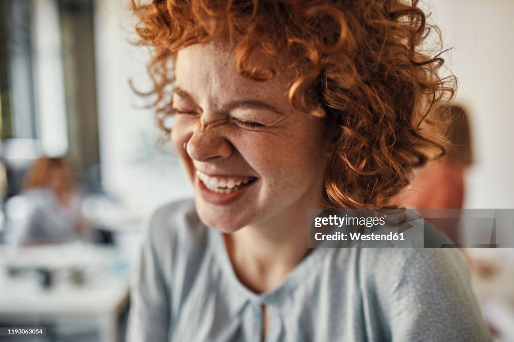 Portrait of a laughing businesswoman with closed eyes in office