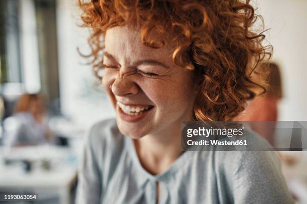portrait of a laughing businesswoman with closed eyes in office - lachen stock-fotos und bilder