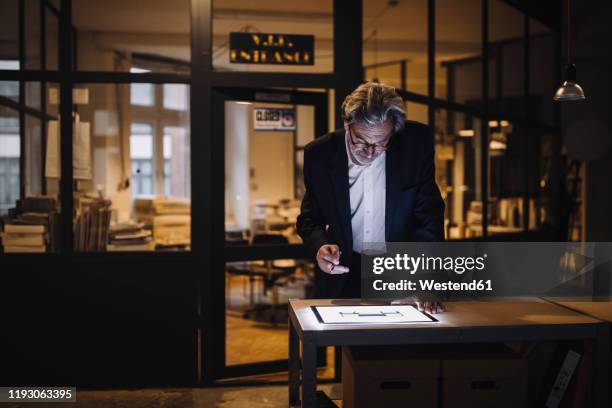 senior businessman looking at shining tablet in office - männerabend stock-fotos und bilder