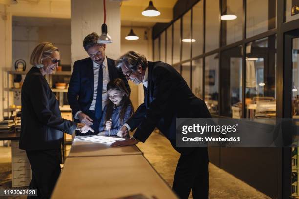 business people and girl looking at shining tablet in office - business relations stock pictures, royalty-free photos & images