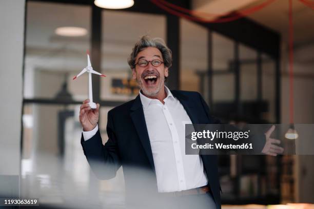 excited senior businessman with wind turbine model in office - alter lustig crazy stock-fotos und bilder