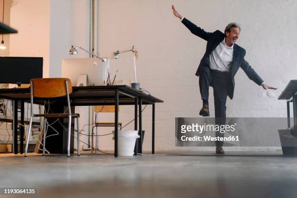 happy senior businessman doing gymnastics in office - standing on one leg stock-fotos und bilder
