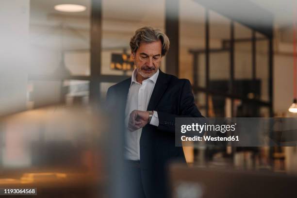 senior businessman checking the time in office - time management stock pictures, royalty-free photos & images