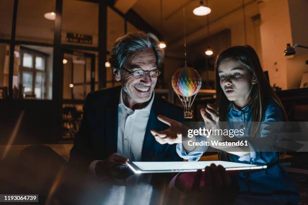 happy senior buisinessman and girl with hot-air balloon and shining tablet in office - kid chef stock-fotos und bilder