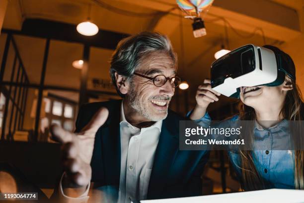 happy senior buisinessman and girl wearing vr glasses with hot-air balloon in office - family portrait 3d stockfoto's en -beelden
