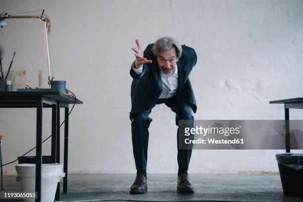 senior businessman doing gymnastics in office - bukken stockfoto's en -beelden