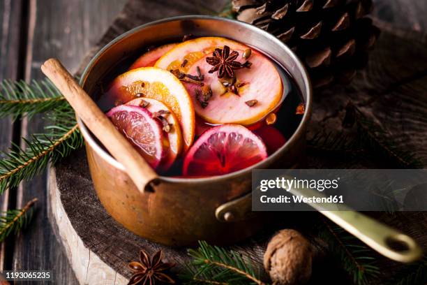 mulled wine with oranges and cinnamon in a saucepan - glühwein stock-fotos und bilder