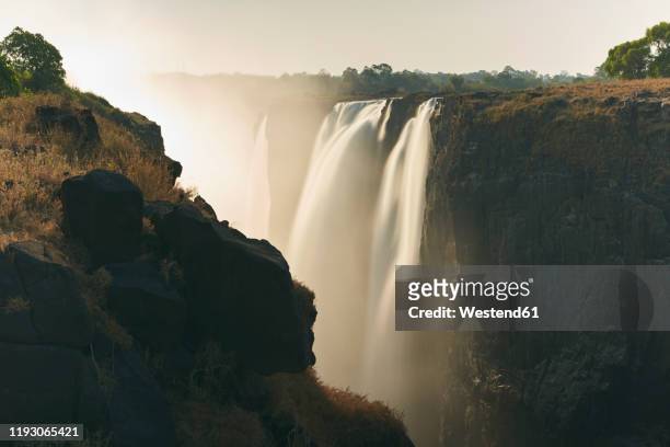 view of victoria falls at sunset, zimbabwe - victoria falls sunset stock pictures, royalty-free photos & images