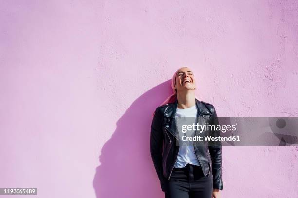 portrait of laughing woman with pink headscarf, has cancer - leather jacket stockfoto's en -beelden