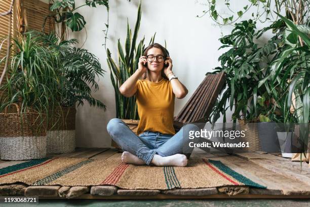 relaxed young woman sitting on the floor at home listening to music - listening imagens e fotografias de stock
