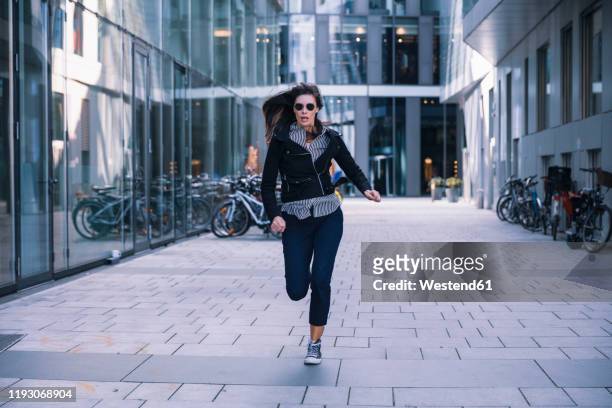 woman with sunglasses running away - flüchten stock-fotos und bilder