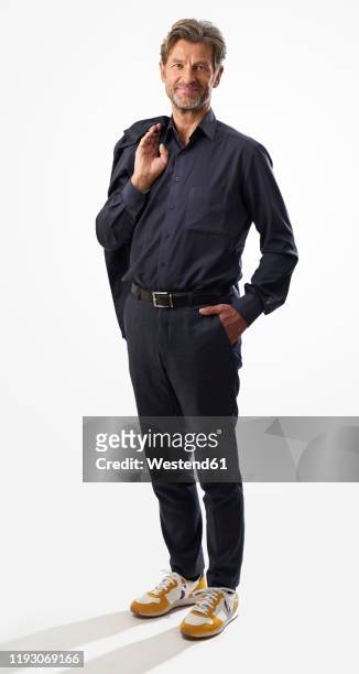 portrait of confident mature businessman standing against light background - ganzkörperansicht stock-fotos und bilder
