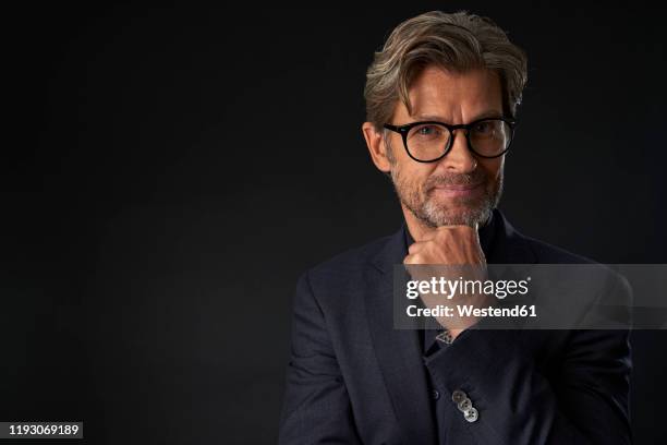 portrait of mature businessman wearing glasses against dark background - male man portrait one person business confident background stockfoto's en -beelden