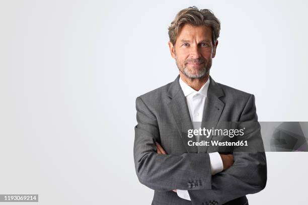 portrait of smiling mature businessman against light background - mann stolz stock-fotos und bilder